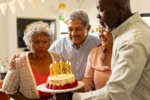 elderly woman surrounded by family blowing out candles on birthday cake